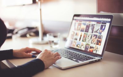 Close-up of hands typing on a laptop with an image gallery open on the screen.