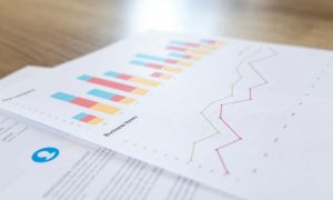 A close-up view of a business document with charts and graphs on a wooden desk.