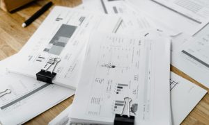 A stack of financial reports and graphs with clips on a wooden desk, highlighting business planning.