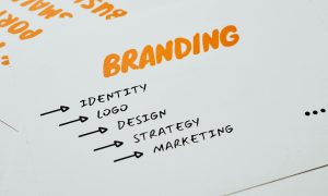 Close-up of a paper with branding, identity, design, strategy, and marketing concepts in orange and black.
